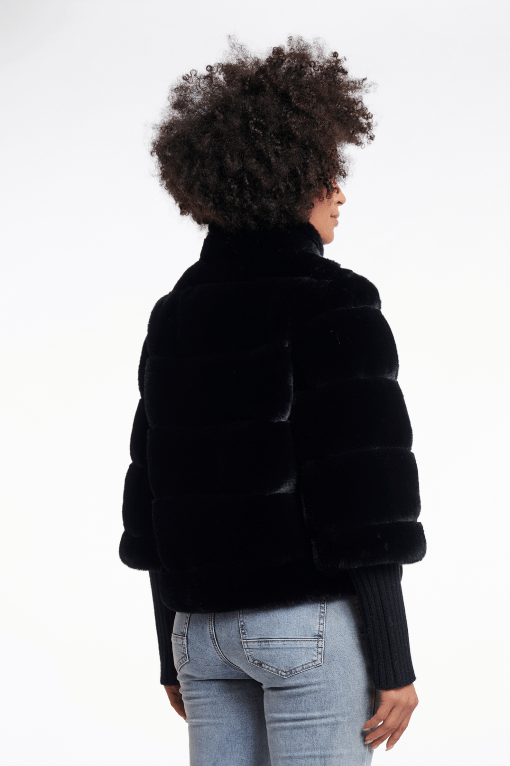 Person wearing a black fur jacket on a white background