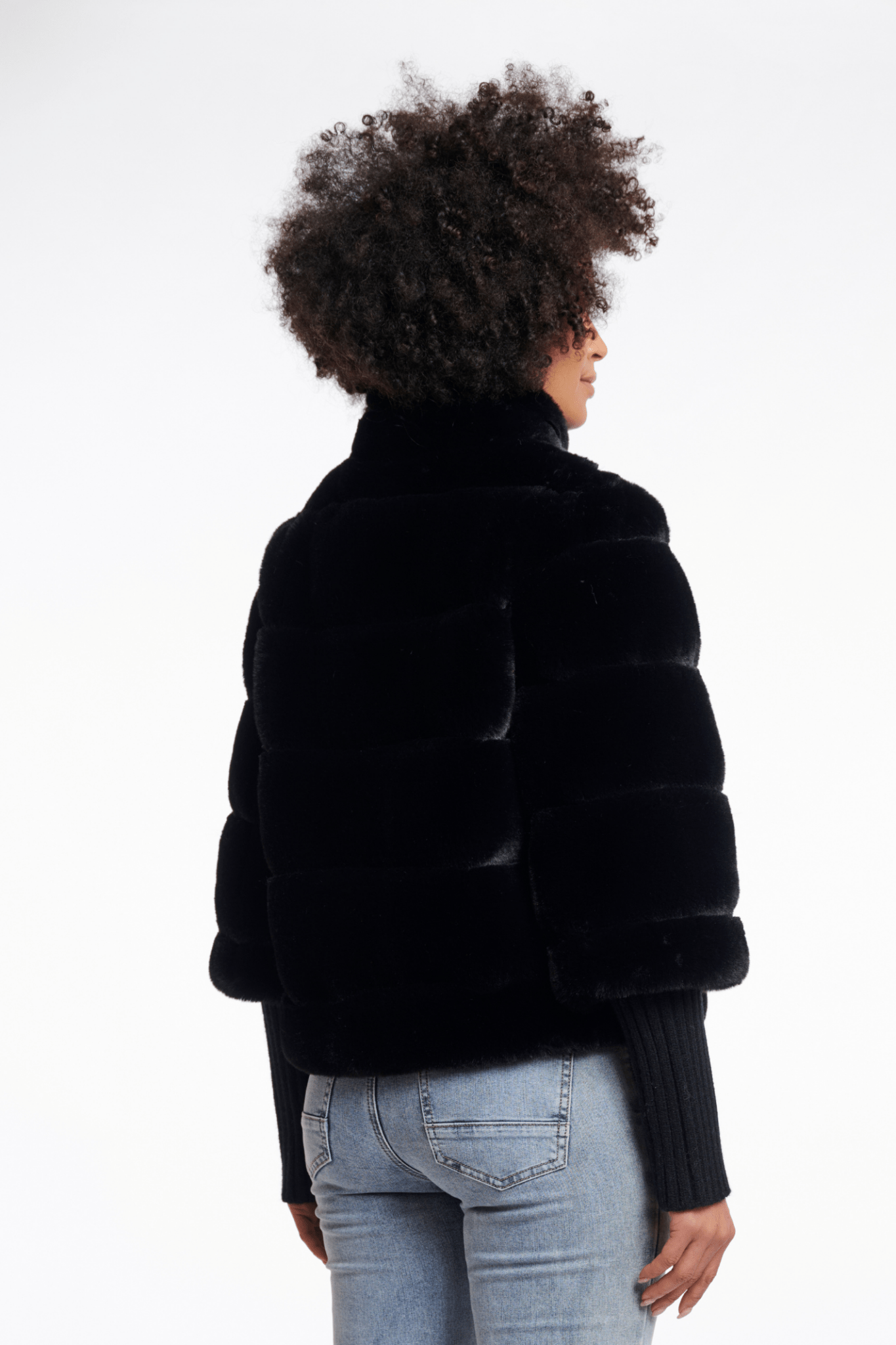 Person wearing a black fur jacket on a white background