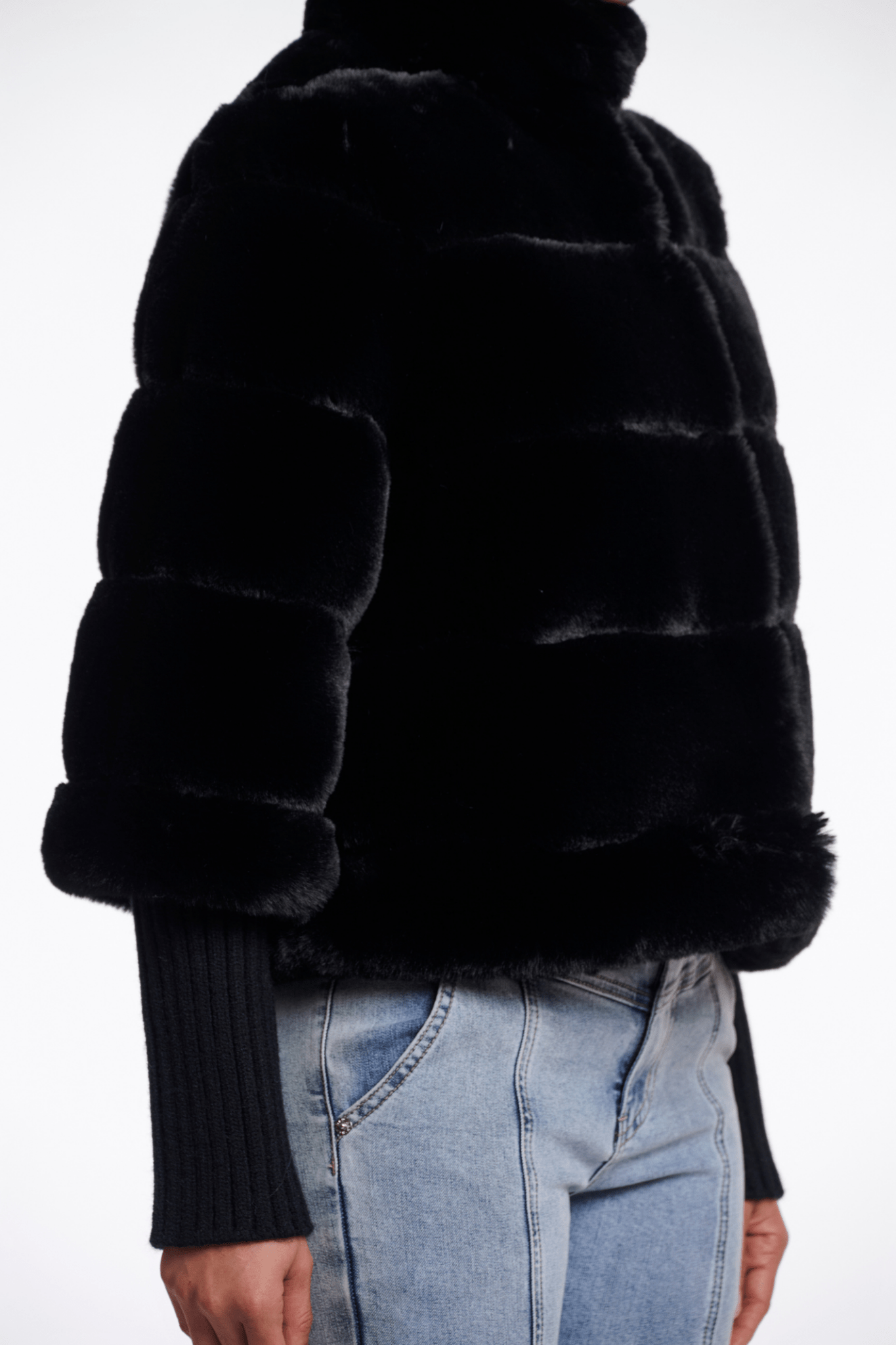 Black fur jacket worn by a person on a white background