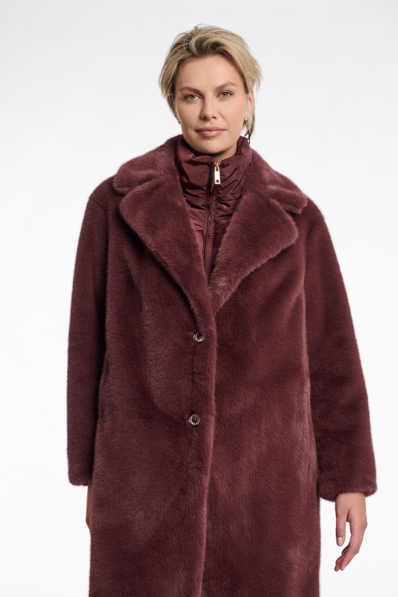 Woman wearing a long burgundy coat on a white background