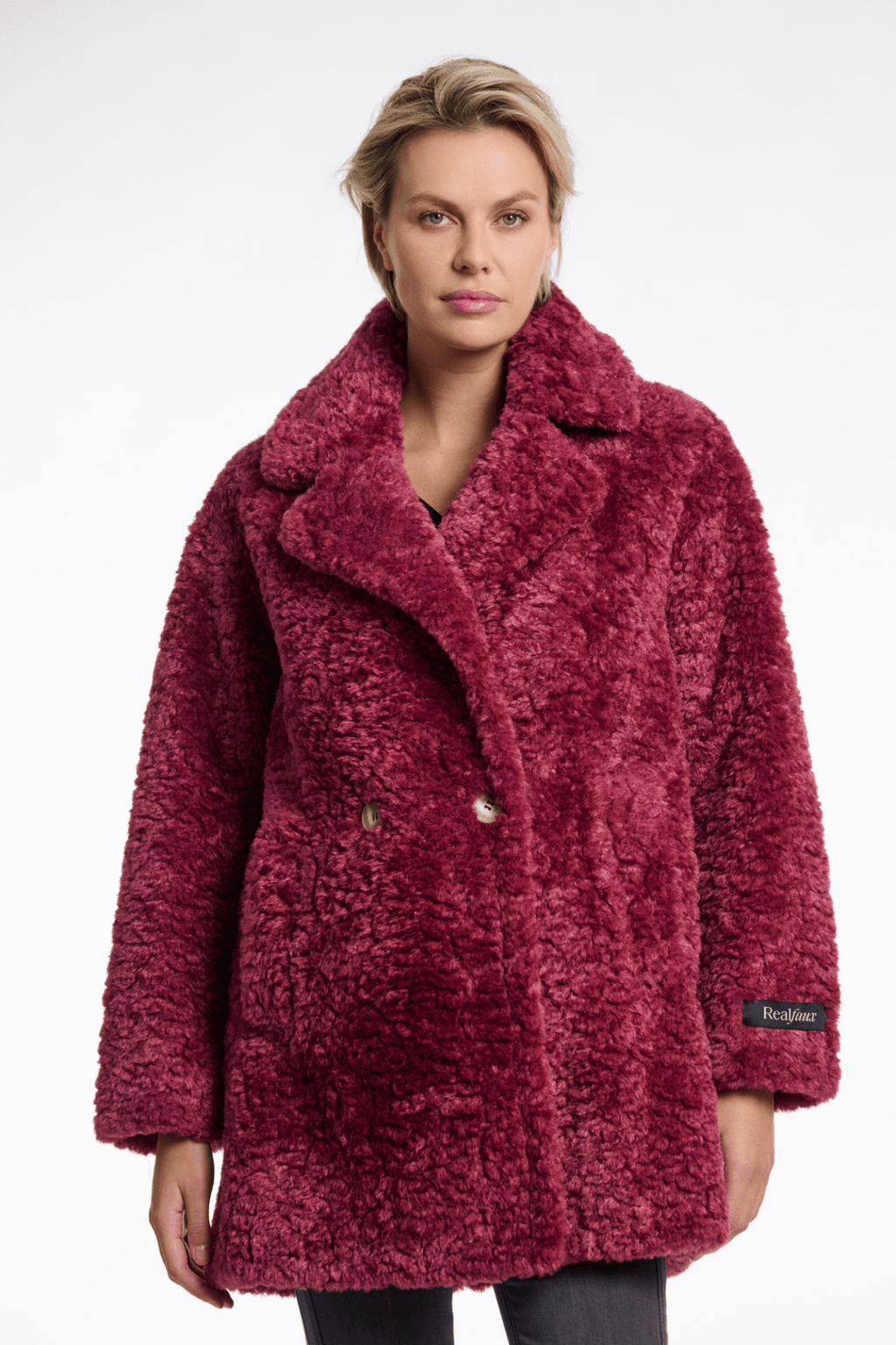 Woman wearing a red textured coat with a brand logo on a white background