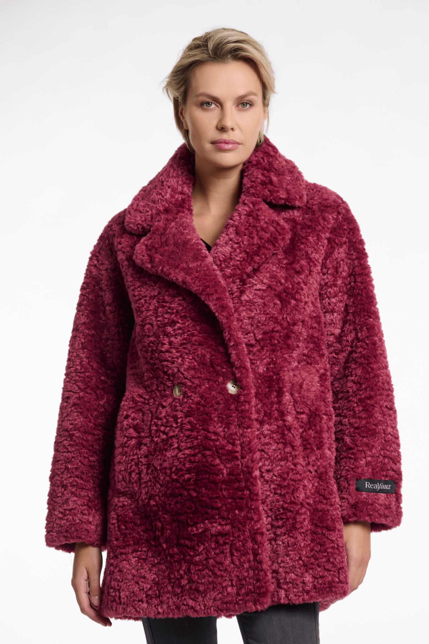 Woman wearing a red textured coat with a brand logo on a white background