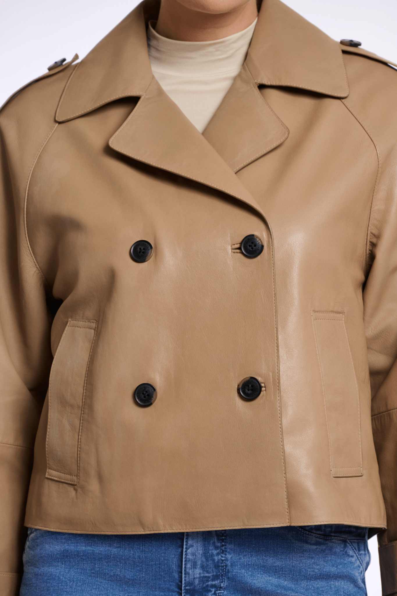 Tan trench coat with black buttons on a white background