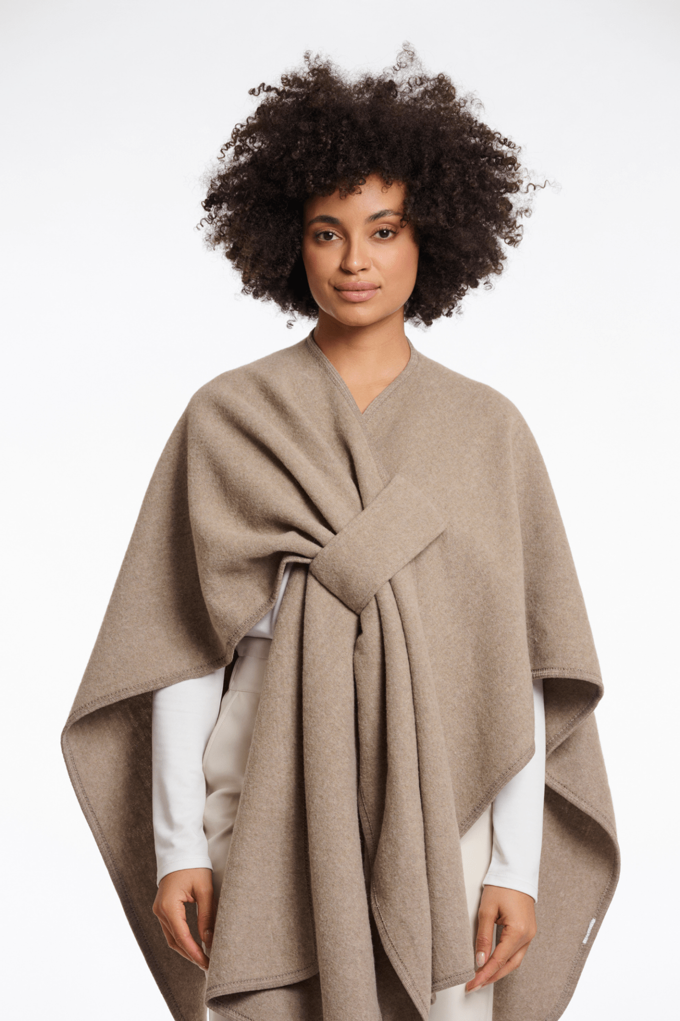 Woman wearing a beige poncho against a white background