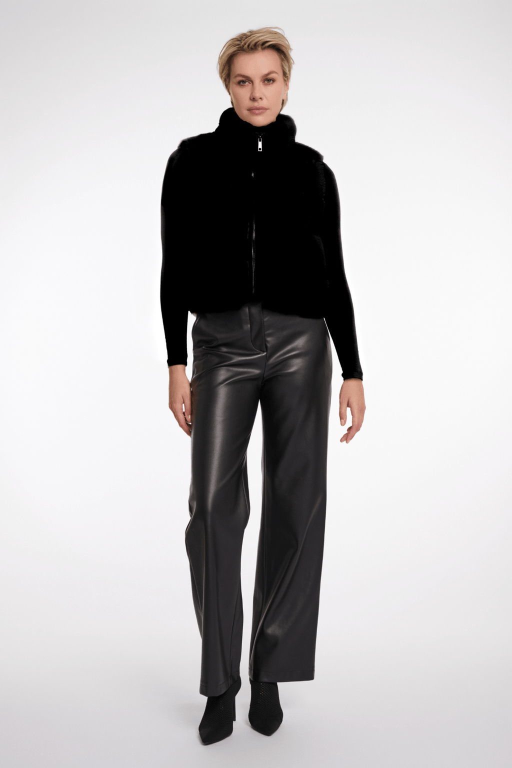 Person wearing a black jacket and leather pants on a white background