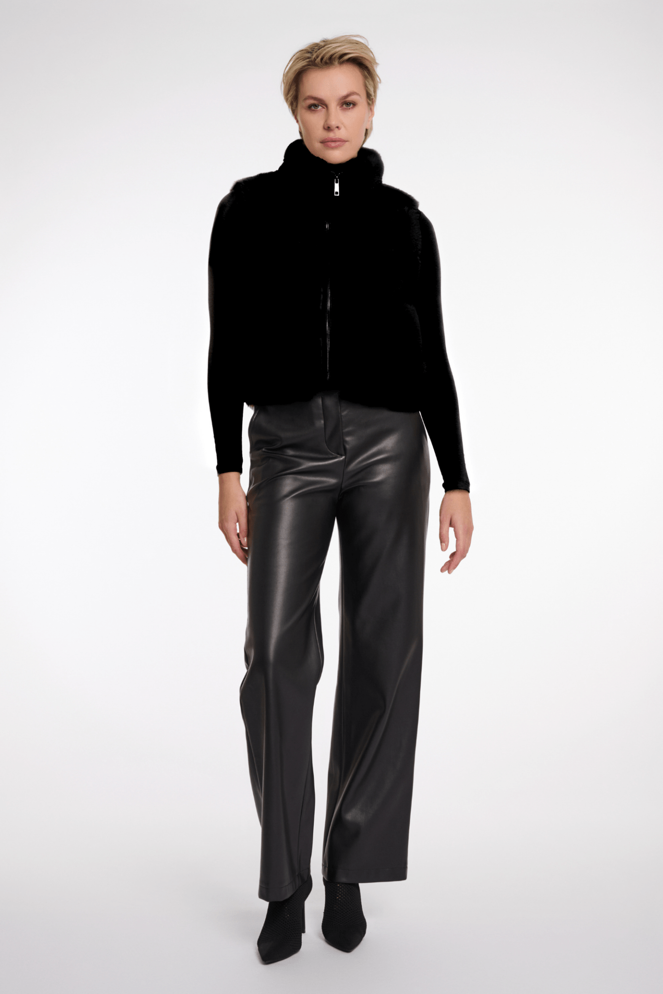 Person wearing a black jacket and leather pants on a white background