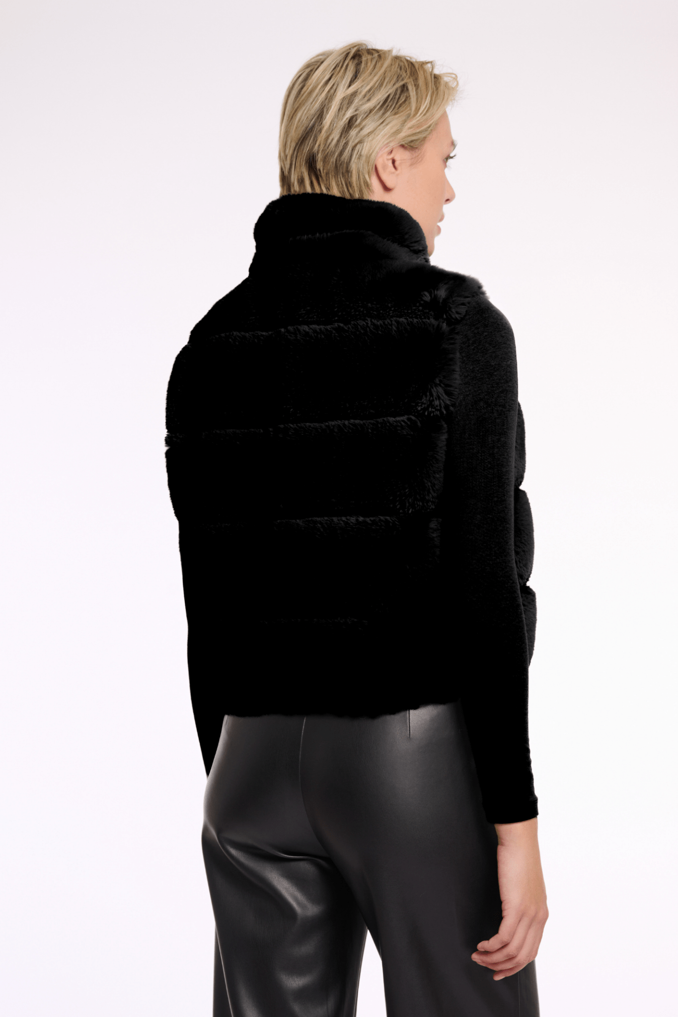 Person wearing a black puffer jacket and black pants on a white background