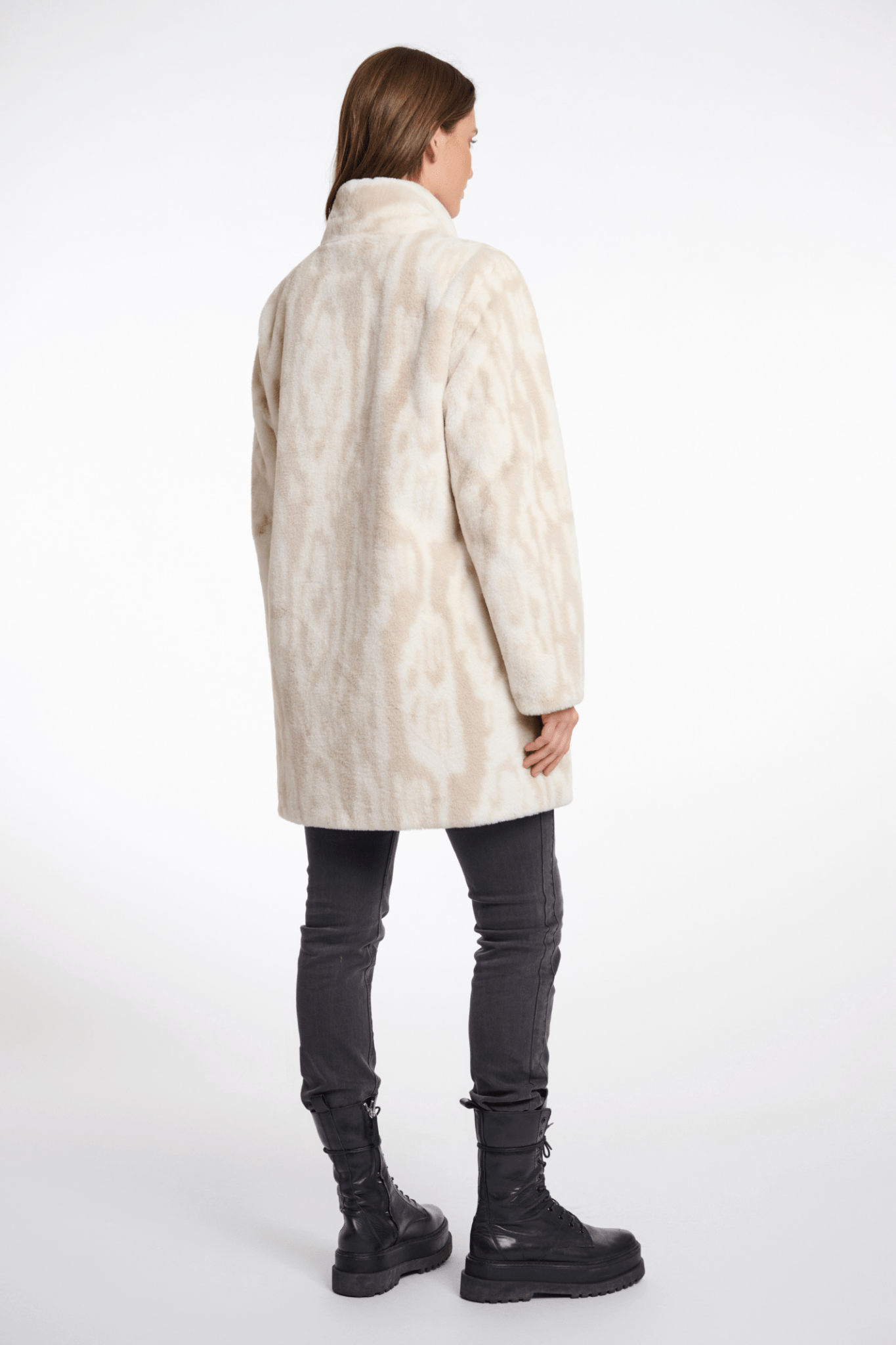 Person wearing a cream-colored coat on a white background
