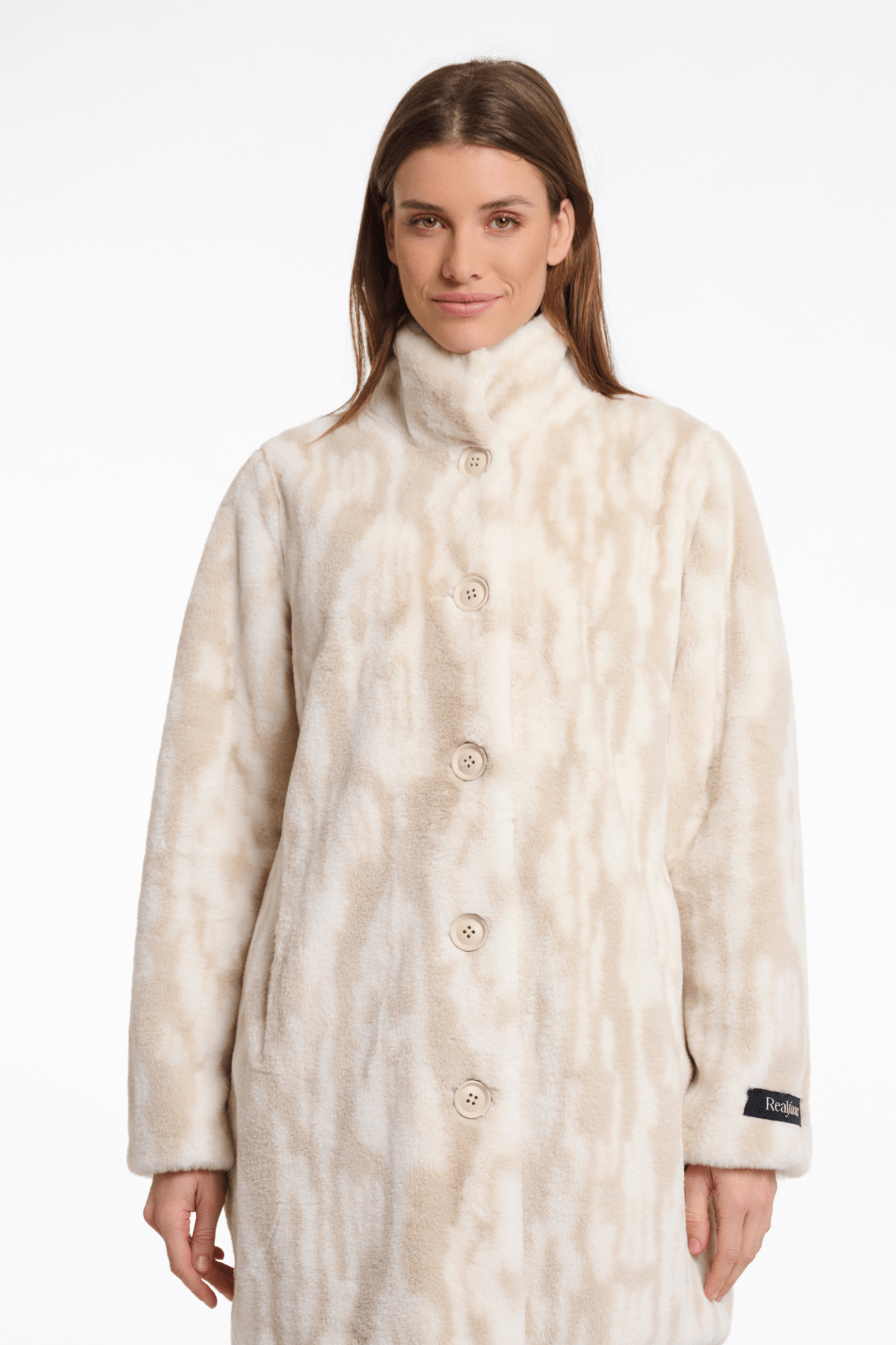 Woman wearing a long, light-colored coat with a pattern on a white background