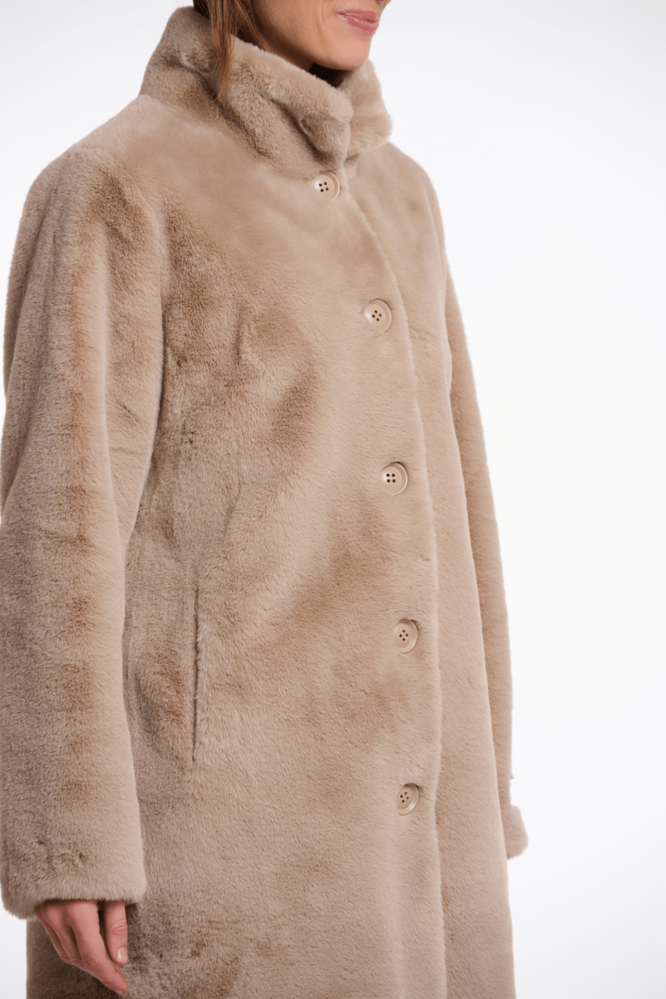 Beige fur coat worn by a person on a white background
