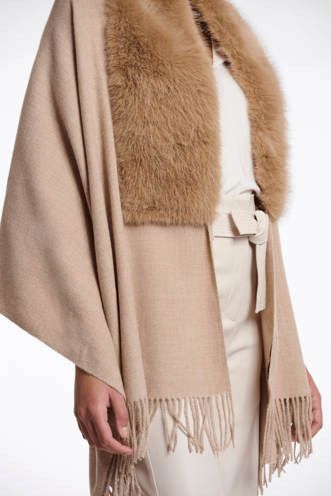 Beige poncho with fur trim and fringes on a white background