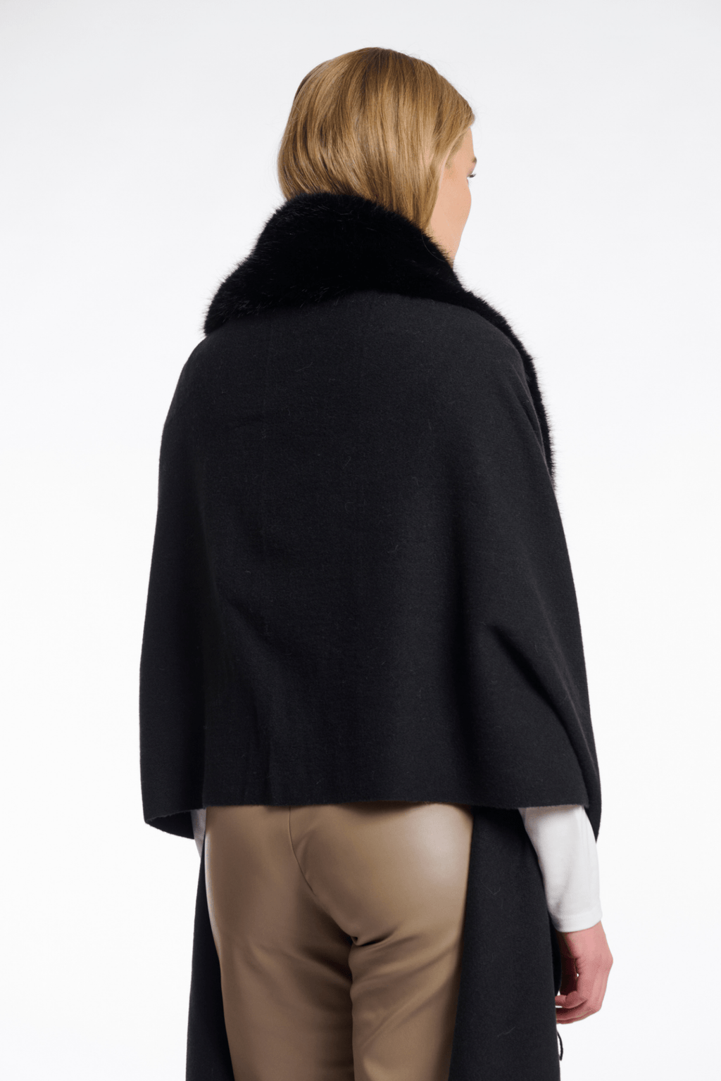 Person wearing a black coat with fur collar on a white background