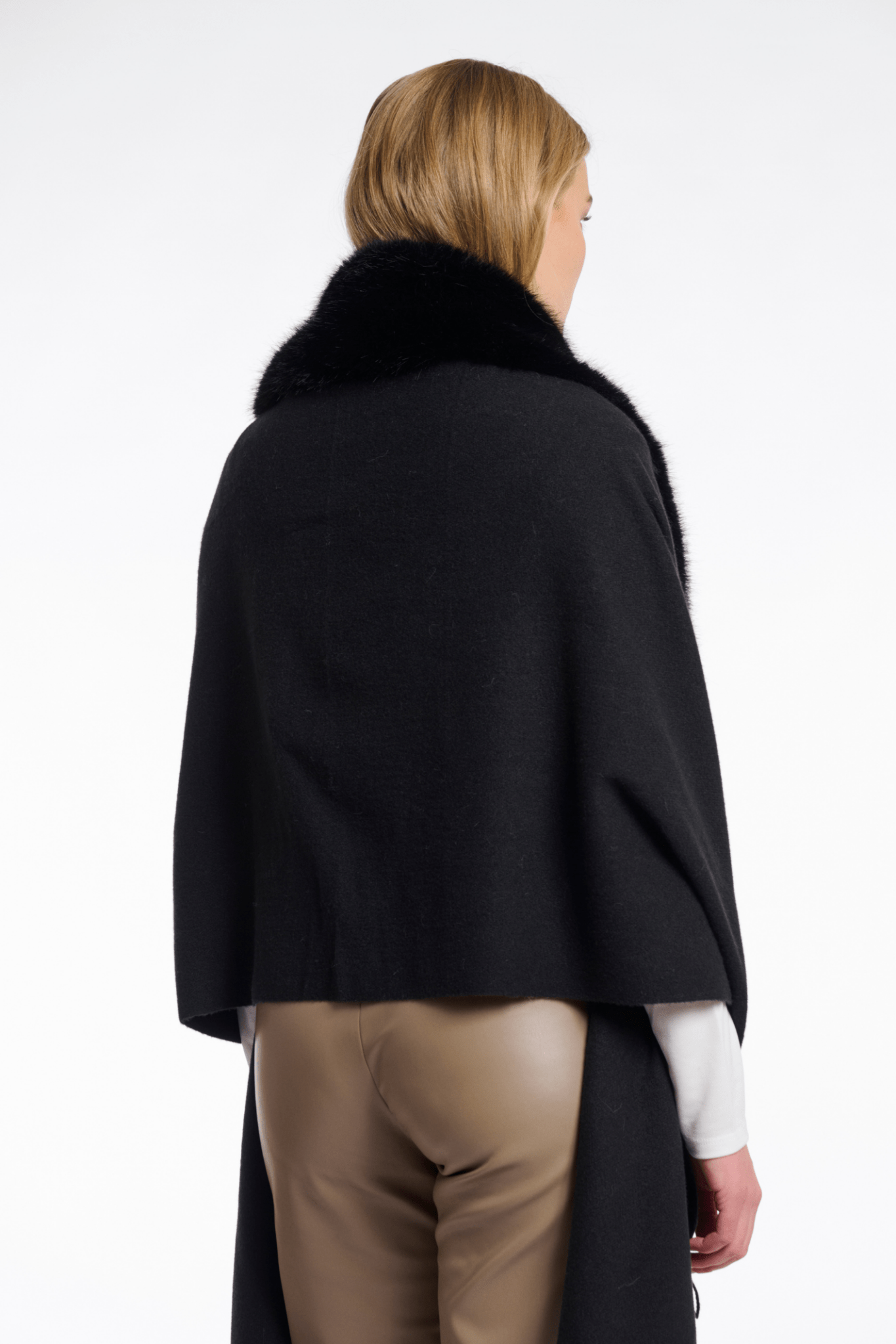 Person wearing a black coat with fur collar on a white background