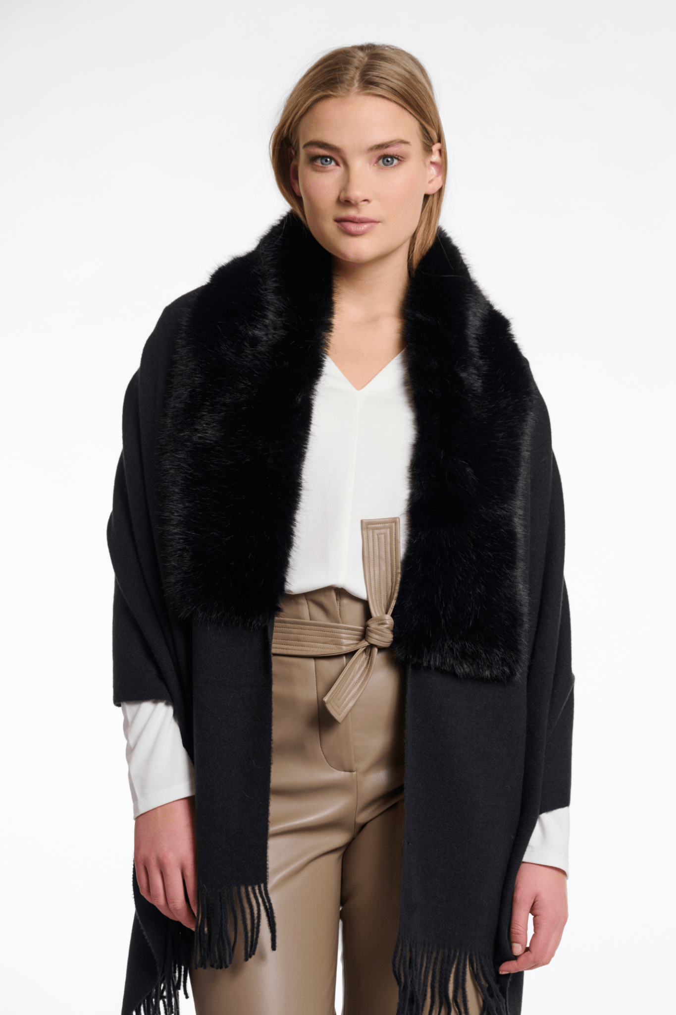 Woman wearing a black fur-trimmed coat with a white background