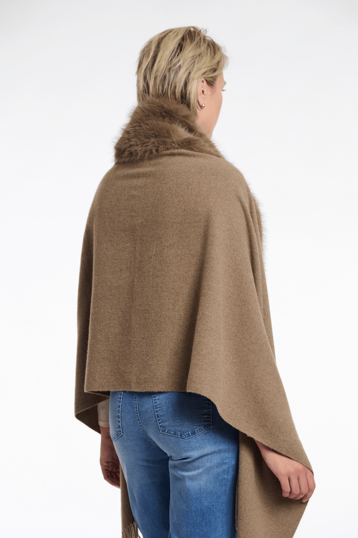 Person wearing a brown poncho with fur collar on a white background
