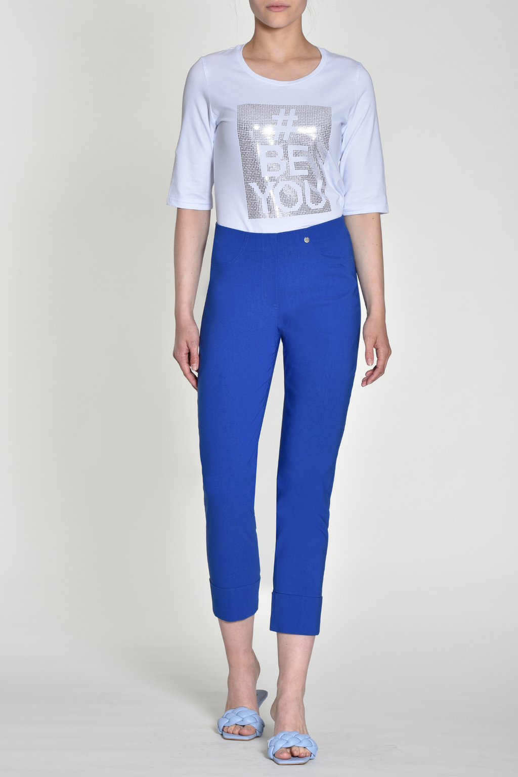 Woman wearing royal blue tailored stretch trousers with cuffed hems and elastic waistband on light background