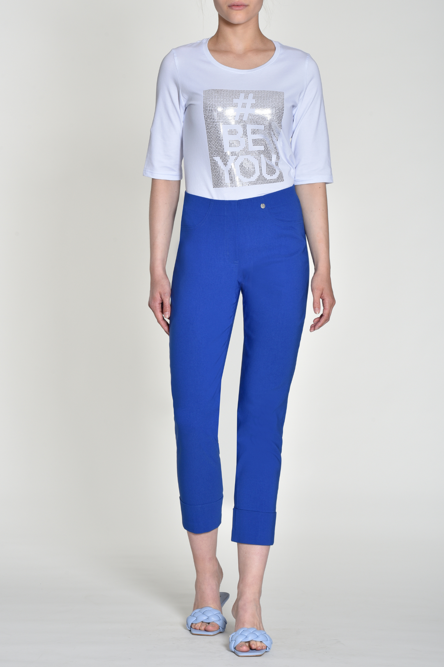 Woman wearing royal blue tailored stretch trousers with cuffed hems and elastic waistband on light background
