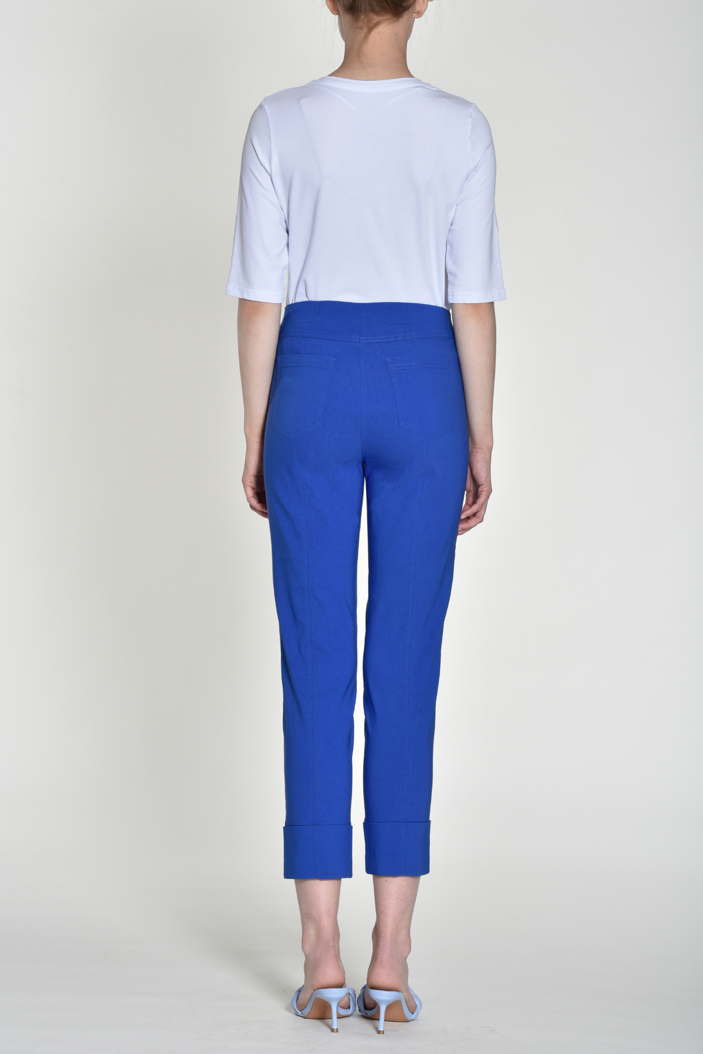 Back view of woman wearing royal blue slim-fit cropped trousers with cuffed hems and elastic waistband