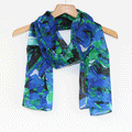 Blue and green abstract patterned lightweight scarf displayed on wooden hanger against white background