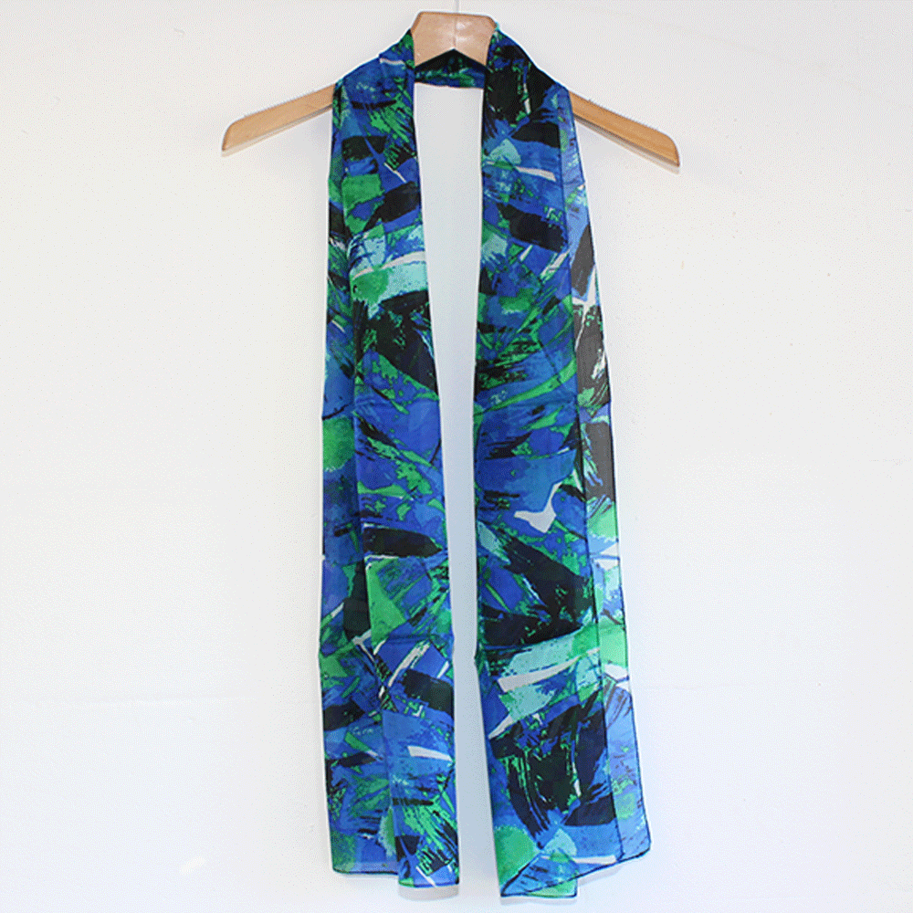 Long lightweight scarf with blue, green, and black abstract brushstroke design hanging on wooden hanger